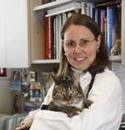 Dr. Ann Hohenhaus of the Animal Medical Center holding a cat while they both look into the camera