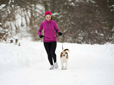 Woman running in snow with dog