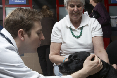 A client and veterinarian pet a seeing eye dog in the Animal Medical Center's waiting room