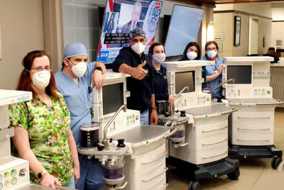 A team of veterinarians wearing masks stands around four ventilators
