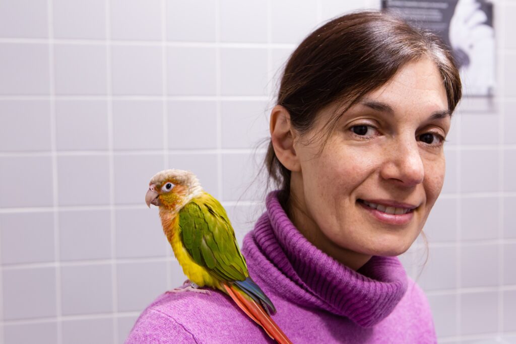 A woman with a pet bird on her shoulder