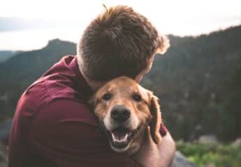 A man hugging a dog in nature