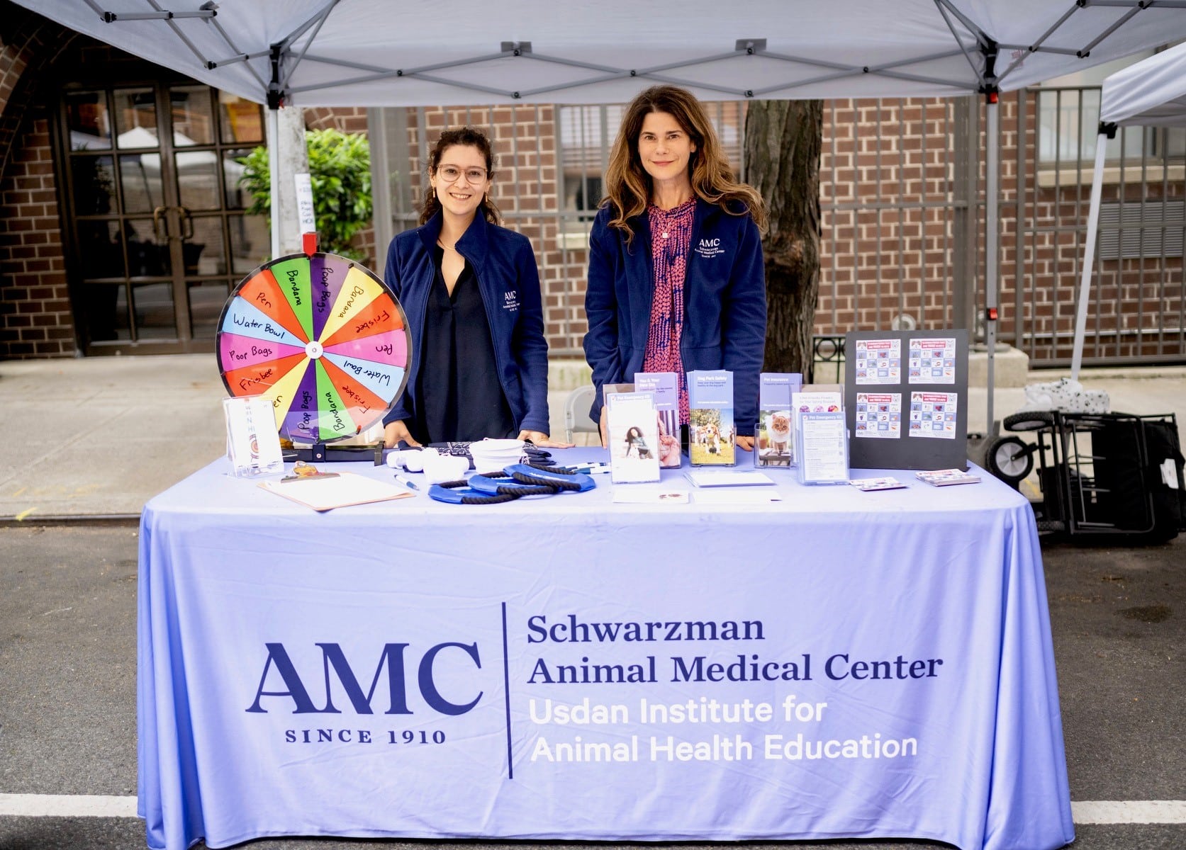 The team from the Usdan Institute for Animal Health Education standing behind their table with informational resources for pet owners at the Muddy Paws Block Party.